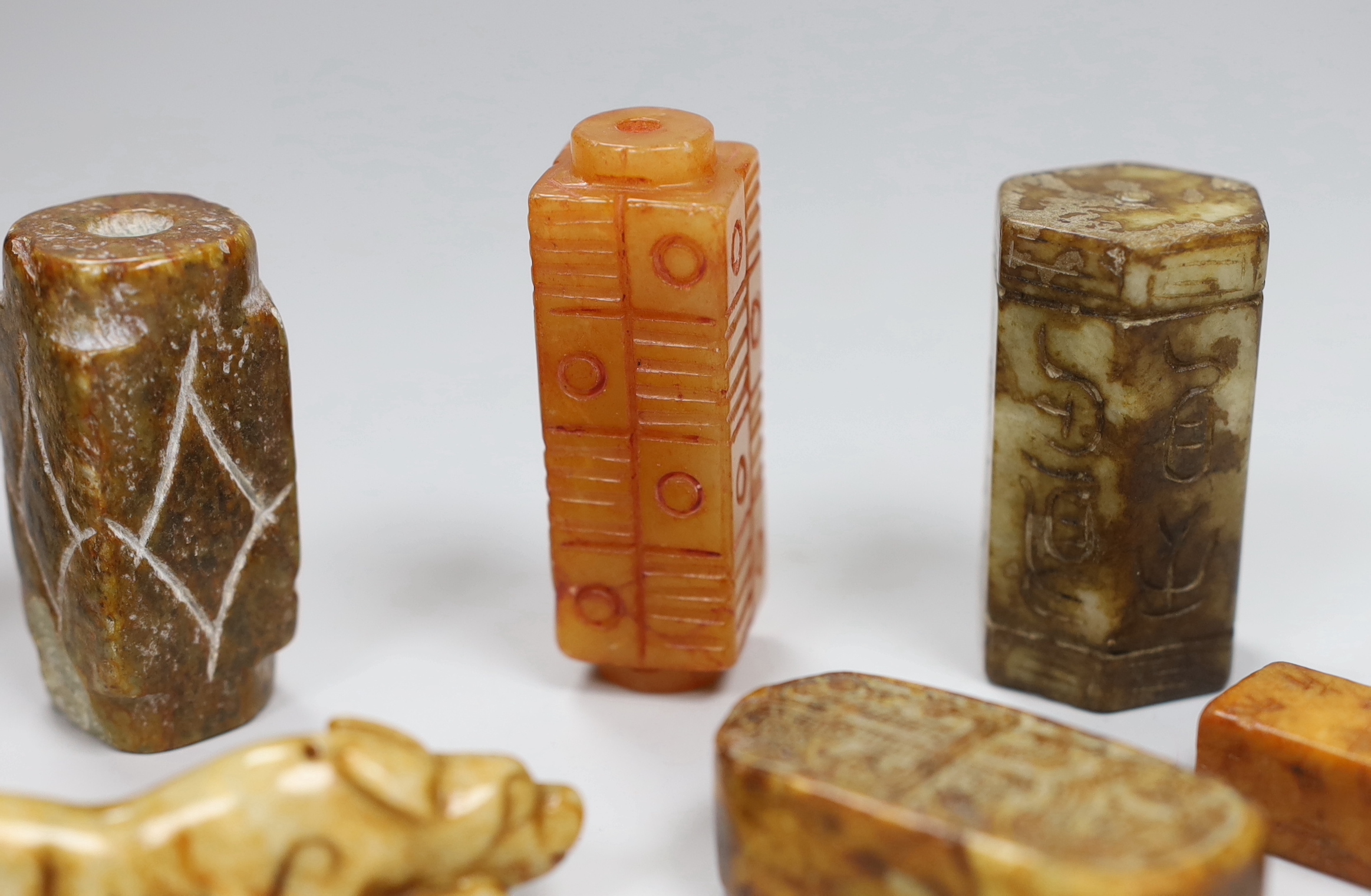 Eight Chinese archaistic jade or hardstone pendants/beads with carved decoration, the largest 9cm wide